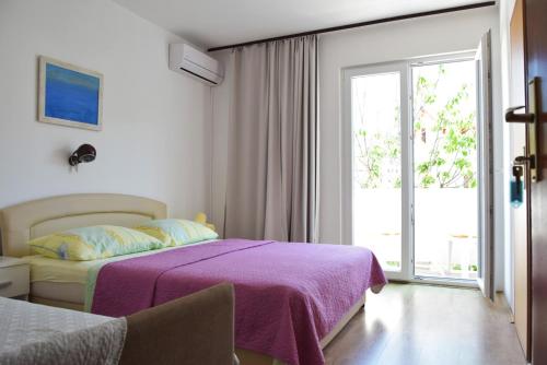 - une chambre avec un lit doté d'une couverture violette et d'une fenêtre dans l'établissement Guest house Tina, à Rab