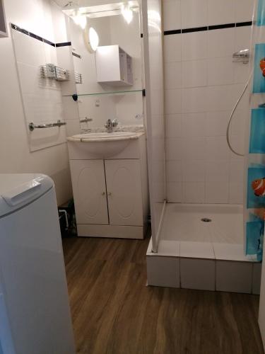 une salle de bain blanche avec un lavabo et une douche dans l'établissement Jolie maison familiale oleronaise, à Saint-Georges-dʼOléron