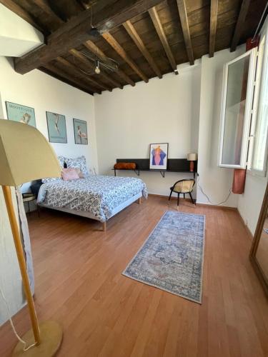 a bedroom with a bed and a rug on a wooden floor at Duplex de charme 80m2 au coeur d'Arles, 2 chambres in Arles