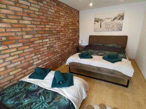 Dos camas en una habitación con una pared de ladrillo. en Siedlisko PoMaLeńku, en Żarnowska