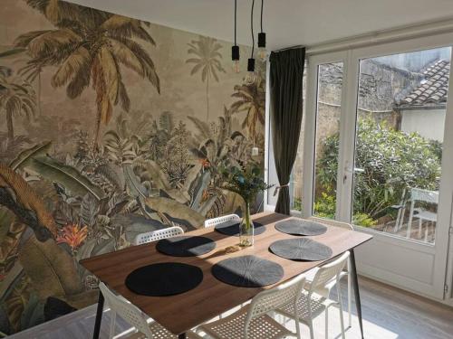 a dining room table with chairs and a tropical wallpaper at Agréable maison de ville, de 1 à 6 personnes, à 5 min à pied du centre ville de Cognac in Cognac