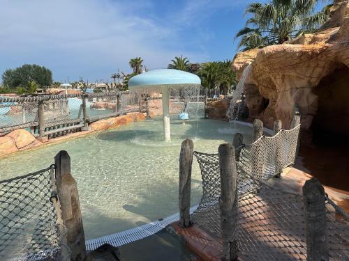une piscine avec un parasol dans un parc aquatique dans l'établissement Mobil home les sables d or, au Grau-dʼAgde