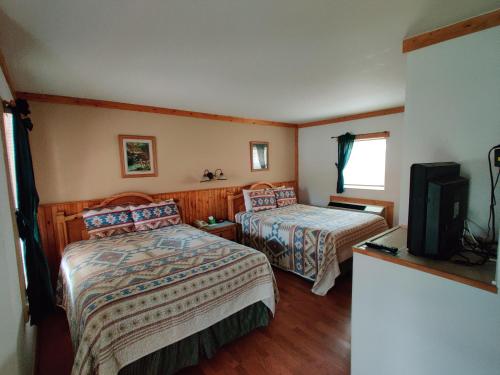 a hotel room with two beds and a television at Smoky Falls Lodge in Maggie Valley