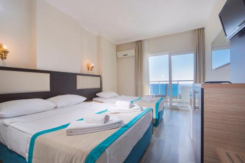 a hotel room with two beds and a television at Club Sun Paradise Hotel - All Inclusive in Avsallar