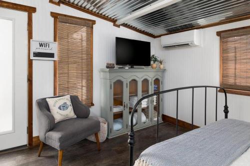 a bedroom with a bed and a chair and a television at NEW! Ladybug @ Firefly Grove w/ Blanco River Access in Wimberley