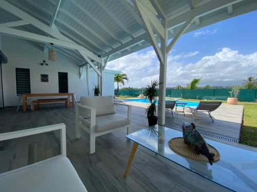 a patio with a table and a chair and a glass table at VOIR com 5 étoiles airb, Villa Zolenzo, la tête dans les montagnes, 10 pers in Petit-Bourg