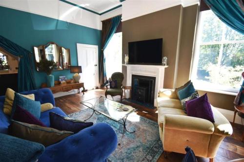 a living room with blue furniture and a fireplace at The Huntress Suite in Buxton