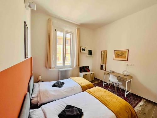 a bedroom with two beds and a desk and a window at Casa Bonita Bolognina in Bologna