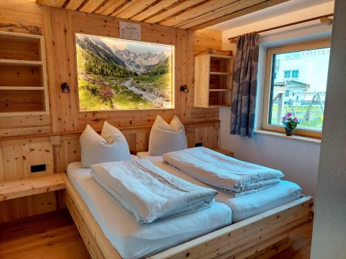 two beds in a wooden room with a window at Tristner Appart in Schwendau