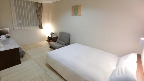 ein Hotelzimmer mit einem weißen Bett und einem Stuhl in der Unterkunft Yurihonjo - Hotel - Vacation STAY 42534v in Yurihonjo