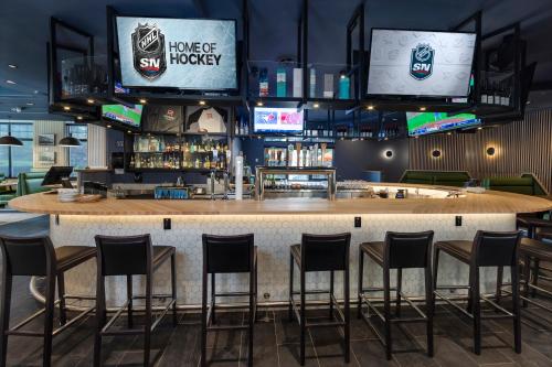 a bar in a restaurant with stools and televisions at Holiday Inn Victoria - Elk Lake by IHG in Victoria