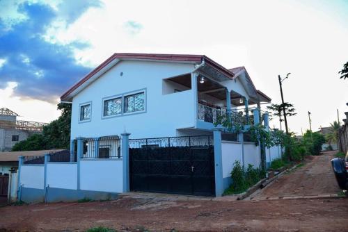 una casa blanca con una valla delante en Appart meuble Jouvence chez Chantal & Francis, en Yaoundé
