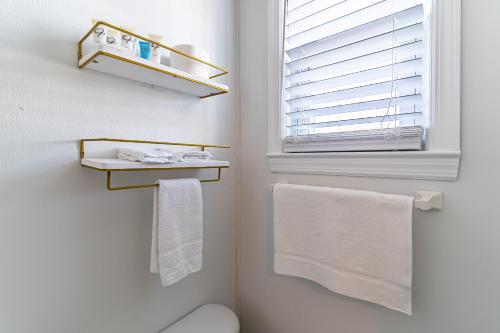 a bathroom with a toilet and a window and towels at Boardwalk Sand & Surf Beach Hotel Oceanfront in Seaside Heights