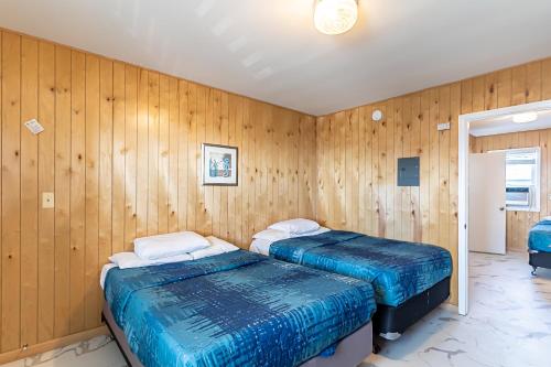 two beds in a room with wooden walls at Boardwalk Sand & Surf Beach Hotel Oceanfront in Seaside Heights
