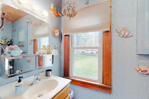 een badkamer met een wastafel, een spiegel en een raam bij Hazen's Hideaway in North Hero