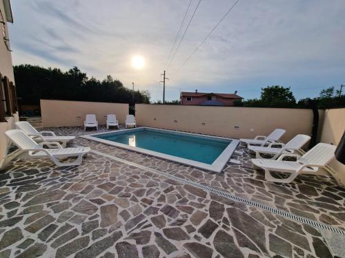 a swimming pool with white chairs and a swimming poolvisor at The Setting Sun in Umag