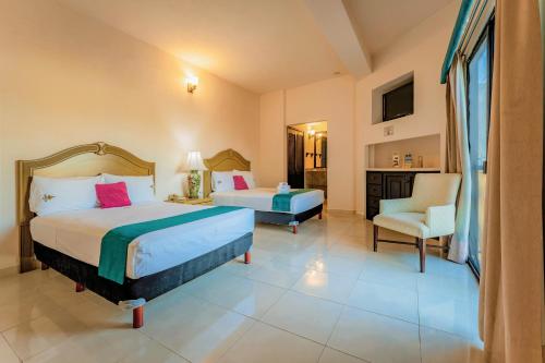 a hotel room with two beds and a chair at Maison del Embajador in Mérida