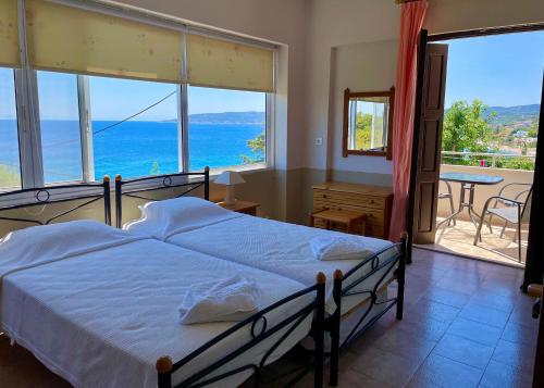 a bedroom with a bed and a view of the ocean at Vasilikos Apartments in Paralia Agias Foteinis