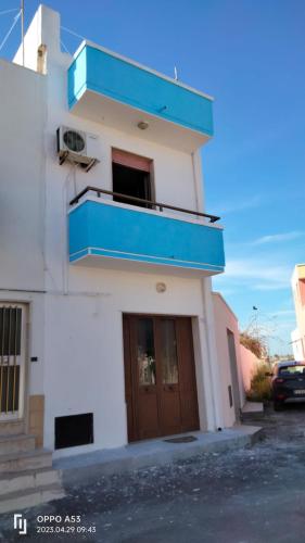 ein weißes Gebäude mit einem blauen Balkon darauf in der Unterkunft Camera in Casa Privata in Torre San Gennaro