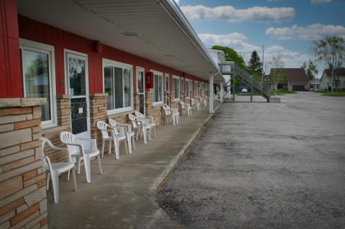 a row of white chairs sitting outside of a building at Maple Leaf Inn & Suites in Kincardine
