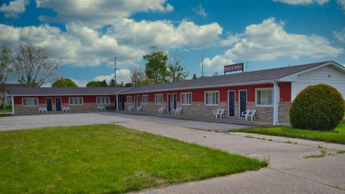 un edificio de escuela roja con sillas delante en Maple Leaf Inn, en Kincardine