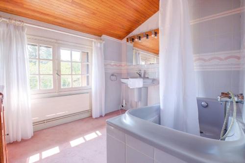 La grande salle de bains est pourvue d'une baignoire et d'une fenêtre. dans l'établissement Bois et chiffons famille et confort, à Siorac-en-Périgord