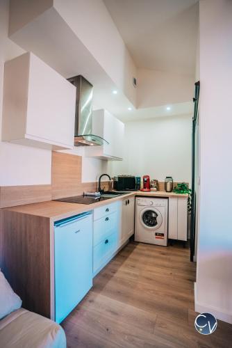 une cuisine avec des armoires blanches et un four à plaques de cuisson dans l'établissement Studio centre-ville (Ecusson), à Nîmes