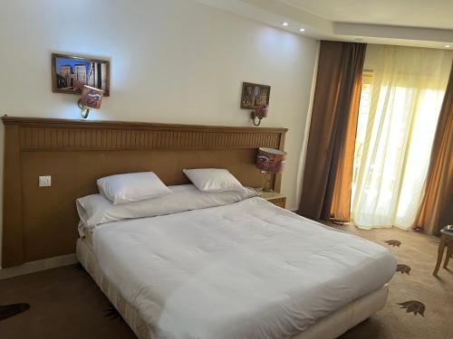a bedroom with a large bed with white sheets at New eliet pyramids view hotel in Qaryat ash Shamālī