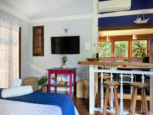 a bedroom with a bed and a kitchen with a counter at Casas D'Água Doce - Casa Bambuzinho in Ilhabela