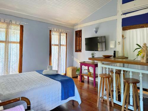 a bedroom with a bed and a kitchen with a bar at Casas D'Água Doce - Casa Bambuzinho in Ilhabela
