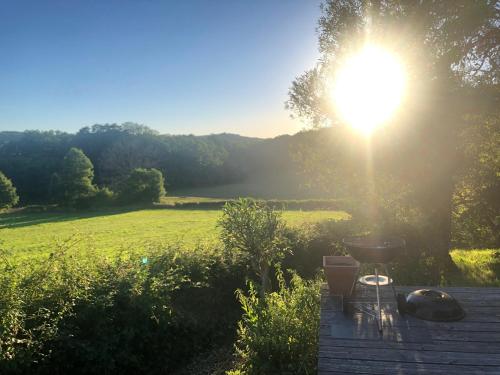 a sun shining on a field with a grill on a deck at Grande maison familiale, rustique et charmante en Bourgogne, dans le Morvan in Dun-sur-Grandry