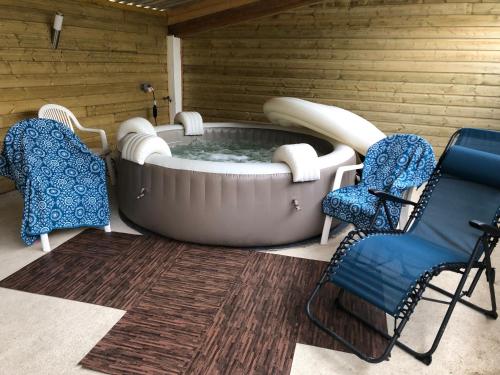 a hot tub in a room with two chairs at gite des 3 pleureuses in Saint-Riquier