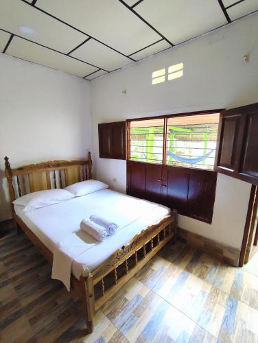 a bedroom with a bed with white sheets and windows at Hostal Casa La Candelaria in Mompós