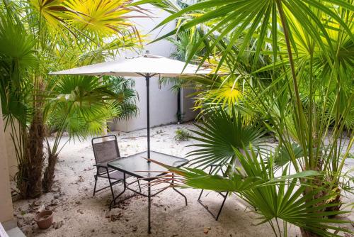 a table and chair with an umbrella and palm trees at 87972 Romantic condo, best retreat for a couple, 1 block from the Ocean in Progreso