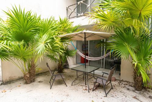 a table and chairs with an umbrella and palm trees at 87972 Romantic condo, best retreat for a couple, 1 block from the Ocean in Progreso