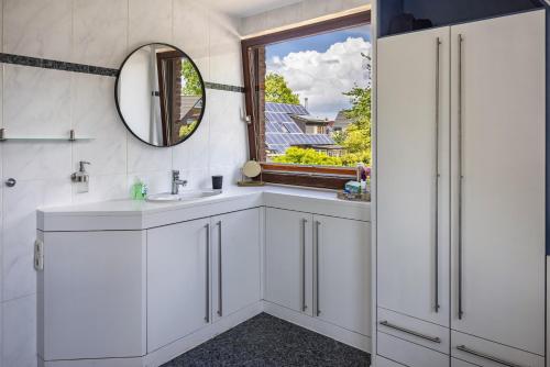 baño con lavabo, espejo y ventana en Ferienhaus Baumann, en Quickborn