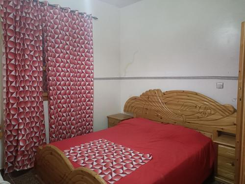 een slaapkamer met een houten bed en een rode deken bij Dar badiawarda in Azilal