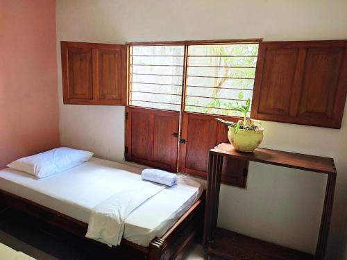 a bedroom with a bed and a window with a plant on a table at Hostal Casa La Candelaria in Mompós