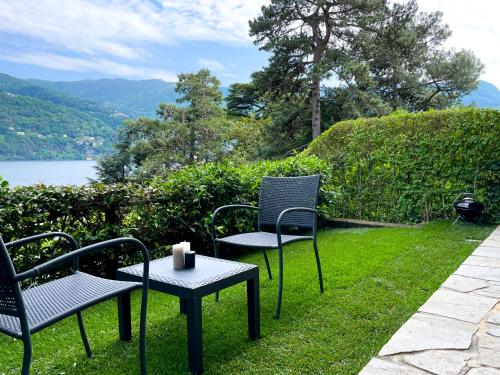 two chairs and a table with a candle on the grass at Regina di Laglio - Free Parking, Garden, Lake View in Laglio