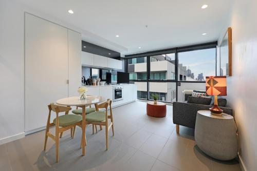 a kitchen and living room with a table and chairs at The Canvas Apartment Hotel in Melbourne
