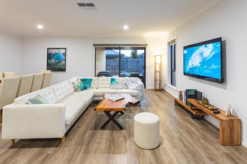 a living room with a white couch and a tv at Sauna, King Beds, Tranquility Base Fun Large Home in Saint Leonards