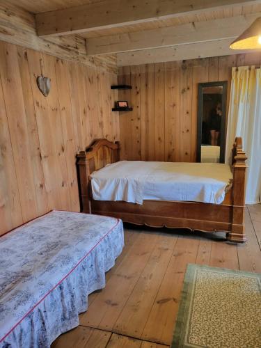 deux lits dans une chambre aux murs en bois dans l'établissement Authentique Maison de campagne De la rivière, à Saint-André-de-Chalencon