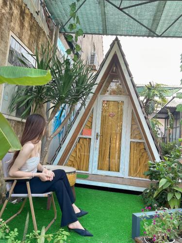 a woman sitting in a chair in front of a house at Trầm Homestay in Thôn An Hòa