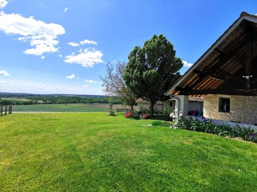 a house with a large grassy yard next to a tree at Gîte de charme dans un cadre calme et reposant in Châtellerault