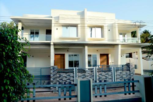 una casa blanca con una valla azul delante de ella en Clover Home, en Thiruvalla
