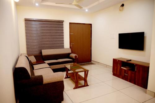a living room with a couch and a tv at Clover Home in Thiruvalla