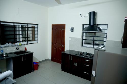 a kitchen with a sink and a refrigerator at Clover Home in Thiruvalla
