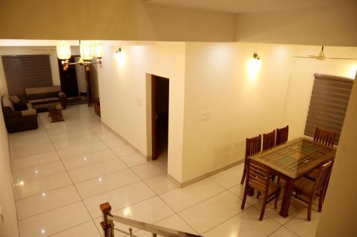 comedor y sala de estar con mesa y sillas en Clover Home en Thiruvalla