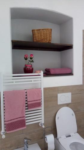 bagno con servizi igienici bianchi e asciugamani rosa di Casa Luisa ad Alba