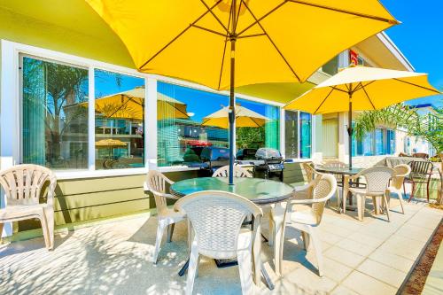 un patio con mesas y sillas y sombrillas amarillas en Surf N Sand 1 & 2 en Newport Beach